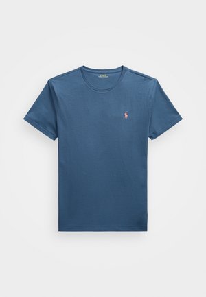 T-shirt bleu à col rond et manches courtes avec un petit logo rose sur la poitrine gauche de Polo Ralph Lauren, présenté à plat sur un fond blanc.
