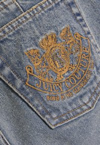 Τζιν τσέπη με κεντητό χρυσό λογότυπο "Juicy Couture" με κορυφή και ζωικά μοτίβα, σε ανοιχτό γαλάζιο υφή ύφασμα.