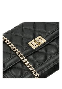 Černá prošívaná kožená taška se zlatým řetízkovým popruhem a obdélníkovým uzávěrem. Vyznačuje se hladkým povrchem a výrazným švem.