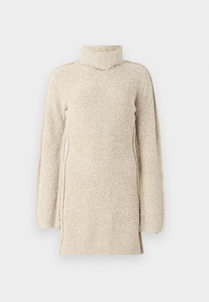 Tunic bej pufos cu guler înalt și mâneci lungi. Prezintă o suprafață texturată și fante laterale pentru confort în mișcare.