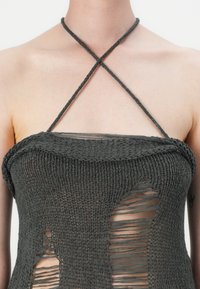 Brown knitted top with a halter neckline, featuring crisscross straps, sheer areas, and irregular slits for texture.
