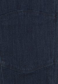 Tela de denim oscuro con una textura suave, con un detalle de costura curva. El material tiene un ligero brillo, enfatizando su rico color.