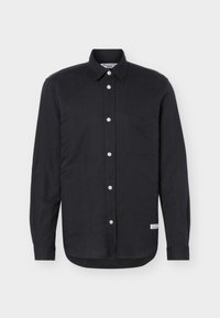 Μαύρο πουκάμισο με μακριά μανίκια και κουμπιά, με μία τσέπη στο στήθος, μυτερό γιακά και μια μικρή λευκή ετικέτα κοντά στο κάτω μέρος του υφάσματος, σε λευκό φόντο.