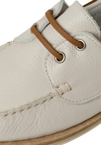 Scarpe in pelle grigio chiaro con finitura testurizzata, dotate di lacci in pelle marrone, occhielli in metallo e cuciture a contrasto lungo i bordi.