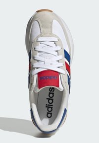 White and beige sneaker with blue and red stripes, lace-up design, textured fabric, and a red tongue featuring the adidas logo.