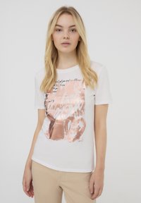 T-shirt bianco a maniche corte con una grafica metallica oro rosa che presenta testo e forme a cuore, realizzato in morbido tessuto di cotone.