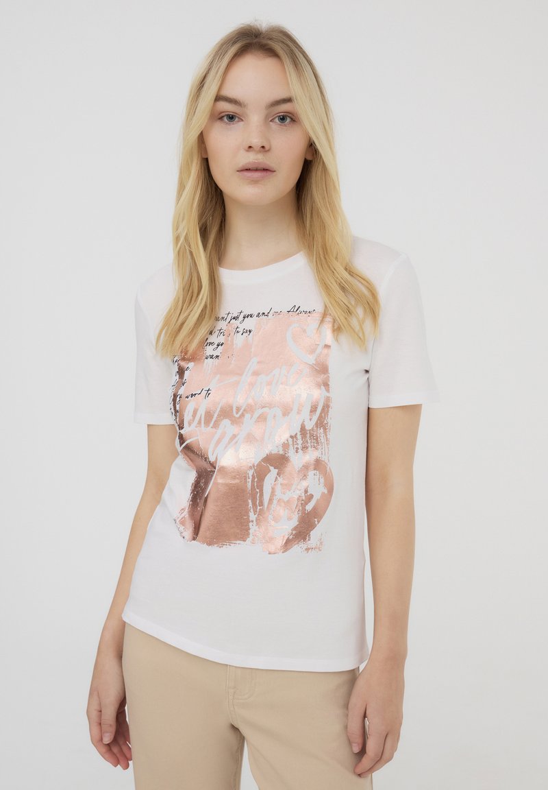 T-shirt bianco a maniche corte con una grafica metallica oro rosa che presenta testo e forme a cuore, realizzato in morbido tessuto di cotone.