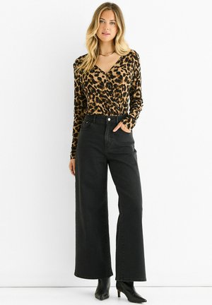 Leopard print long-sleeve top with a V-neck and fitted design paired with high-waisted wide-leg black jeans and black heeled boots.