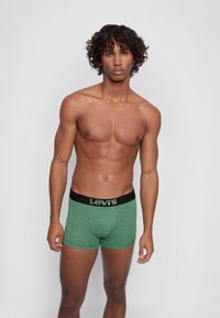 Grüne Baumwollboxershorts mit einem schwarzen elastischen Bund, der das "Levi's"-Logo trägt, mittellang und mit einer glatten Textur.