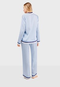 Light blue pajama set with a geometric pattern, featuring long sleeves, navy trim on the collar and cuffs, and loose-fitting pants.