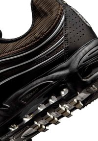Κοντινό πλάνο σόλας μαύρου αθλητικού παπουτσιού με ορατή αερόσολα με την ένδειξη "MAX AIR" και υλικό ανώτερης ύφανσης με υφή δικτυωτού.