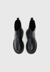 Black ankle boots in smooth leather, featuring a rounded toe, chunky heel, and pull-tab at the back. Durable rubber outsole with ridges.