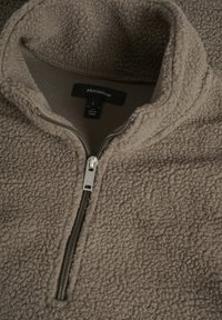 Brun fleece-pullover med høj krave, halv lynlås og struktureret overflade; har en sølv lynlås og et mærke indeni. Størrelse L.