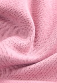 Mäkká ružová pletená tkanina s jemnou textúrou, ktorá sa vyznačuje ľahkým, priedušným dizajnom a hladkým vzhľadom.