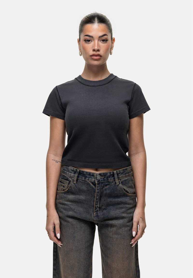 Maglietta nera corta in cotone, con scollatura rotonda e maniche corte, abbinata a jeans in denim scuro a vita alta.