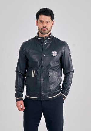 Leder-Bomberjacke in dunklem Navy, mit einem gerippten Kragen, gestreiften Bündchen, Fronttaschen und einem runden Logo-Patch auf der Brust.