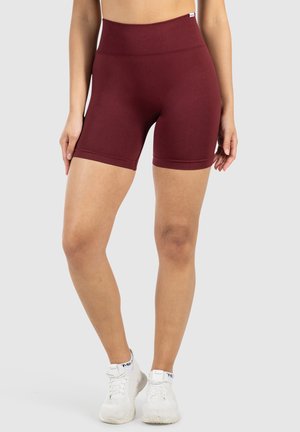 Bordeaux hoge taille shorts met een gladde textuur, voorzien van een brede tailleband en een knielange snit, in combinatie met witte sportieve schoenen.