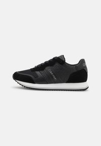 Czarne sportowe sneakersy wykonane z materiału tekstylnego i zamszu, z ozdobną wkładką, białą podeszwą oraz logo po bokach. W komplecie sznurowadła.