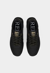 Μαύρα αθλητικά παπούτσια με πλέγμα στα πάνελ, χρυσές λεπτομέρειες στα κορδόνια και στα λογότυπα, επενδεδυμένος γιακάς και υφή στη σόλα. Διαθέτουν ορατή επωνυμία στη γλώσσα.