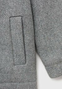 Gray wool coat featuring a patch pocket, a soft texture, and a structured yet relaxed shape. Simple design with no visible hardware.
