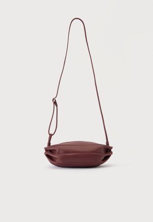 Petit sac bandoulière en cuir grenat avec une fine sangle réglable, présenté à plat sur un fond blanc.