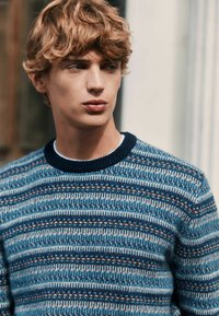 Gestickter Pullover in Blau und Creme mit horizontalen Streifen, ausgestattet mit einem gerippten navyfarbenen Kragen und mehrfarbigen Akzenten im Muster.