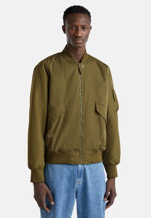 Olivgrüne Bomberjacke mit gerippten Bündchen und Saum, Reißverschluss vorne und Seitentaschen. Der Stoff wirkt glatt und leicht.