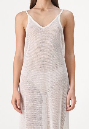 Robe en maille blanche à bretelles spaghetti avec un décolleté en V, présentant un motif en maille ouverte et une silhouette lâche et fluide.