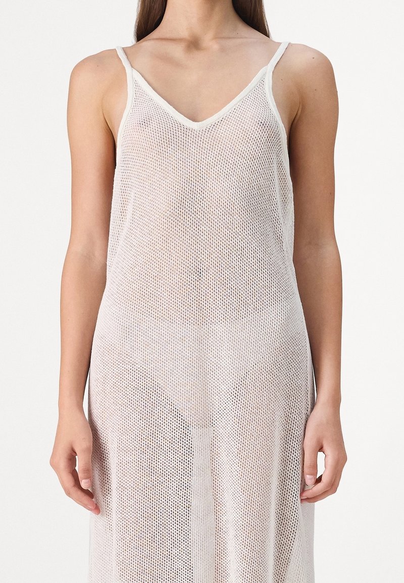 Vestido de tirantes de espagueti blanco de malla con escote en V, que presenta un patrón de tejido abierto y una silueta suelta y fluida.