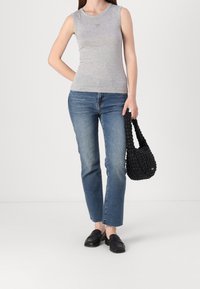 Top senza maniche grigio, jeans azzurri chiari e una borsa intrecciata nera. I jeans hanno un orlo sfilacciato; la borsa presenta un motivo testurizzato. Scarpe slip-on nere.