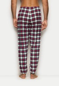 Karierte Baumwollschlafhose mit einem Muster aus roten, grünen und weißen Kästchen, elastischem Bund und schmalen Säumen an den Knöcheln.