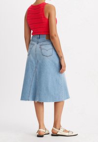 Denim A-linjakjol med fransad fåll, ljusblå färg, midilång design, med bakfickor och detalj med stickningar.