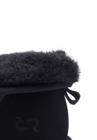 Bota de invierno negra con puño de piel mullida, parte superior texturizada, detalle sutil del logo y cordones de tela para ajuste.