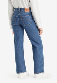 Levi's traperice, visokog struka, plave boje, ravnog kroja s vidljivim šavovima. Na leđima se nalaze dva džepa i kožna oznaka s brendom.