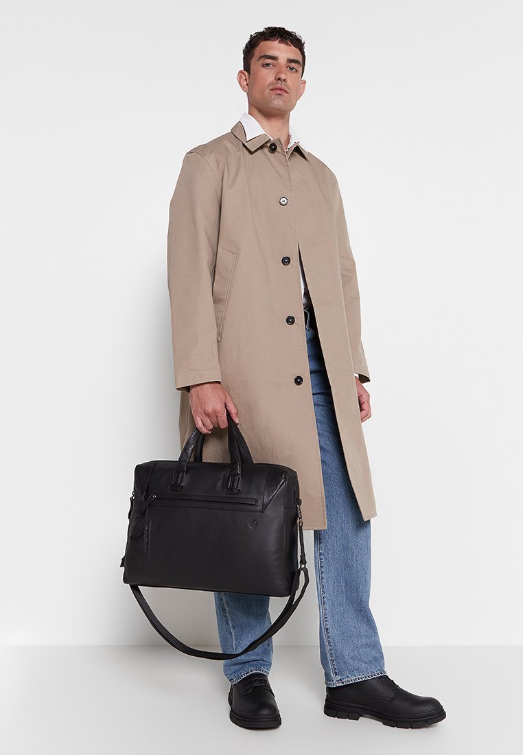 Black leather briefcase with dual handles and detachable shoulder strap. Features front zip pocket and structured design.