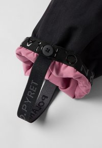 Zwarte stoffen manchet met een roze binnenkant, voorzien van een zwarte knoopsluiting en een band met de tekst "POLAR". Gladde textuur met contrasterende kleuren.