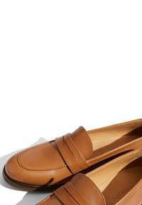 Brune læder loafers med rund tå, der har dekorativ syning og et forhøjet bånd hen over overdelen. Glat tekstur og minimalistisk design.