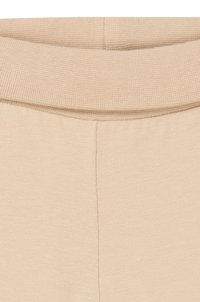 Beige stof met een ribbeltextuur en elastische tailleband. Naaddetails zichtbaar aan de voorkant en achterkant voor een getailleerd uiterlijk.