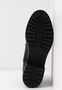 Semelle de botte noire avec un motif profond, taille 37 embossée, et nom de la marque Anna Field visible sur la zone du talon.