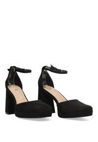 Zapatos de tacón alto de ante negro con correas transparentes en el tobillo, punta cuadrada y tacones de bloque gruesos. Textura suave con un diseño minimalista.