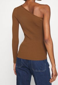 Hnědý žebrovaný pletený top s asymetrickým výstřihem, s jedním dlouhým rukávem a jedním designem s odhaleným ramenem, přiléhavý střih.