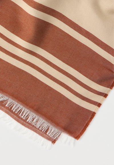 Πλεκτή κουβέρτα με οριζόντιες ρίγες σε τερρακότα και κρεμ αποχρώσεις. Οι άκρες έχουν λεπτομέρεια με φουντίτσες. Μαλακή υφή με διακριτικό μοτίβο.