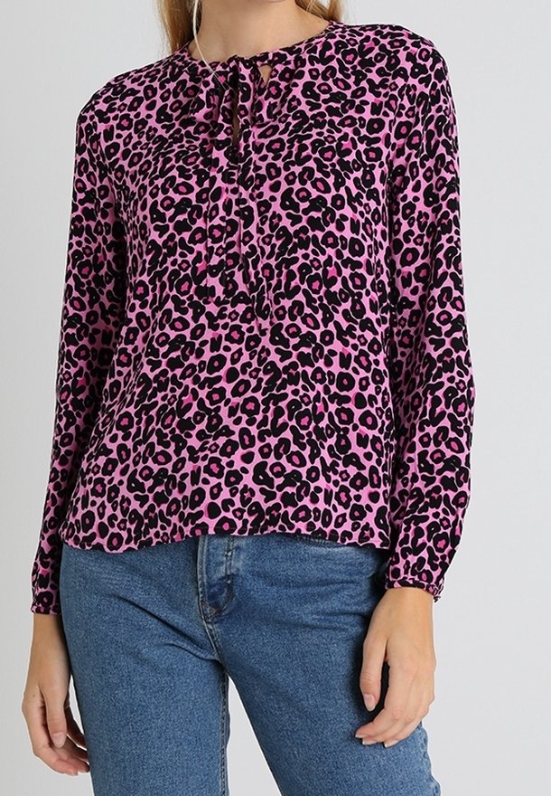 Rosa leopardmönstrad blus med långa ärmar, rund halsringning och en knytdetalj i mitten. Mjukt tyg och ledig passform. Kombinerad med blå jeans.