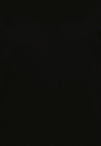 Haut court noir en maille, sans manches, à col montant avec des boutons sur l'épaule gauche.