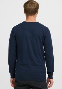 Granatowy sweter z długim rękawem wykonany z dzianiny, z okrągłym dekoltem, ściągaczami na mankietach i u dołu, o gładkiej fakturze.