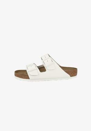 White leather slide sandal with two adjustable buckles, cork footbed, and textured rubber outsole. Open toe and side design.