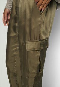 Olijfgroene satijnen cargo broek, met een zijzak, een gladde textuur en een relaxed fit, met een subtiele glans.