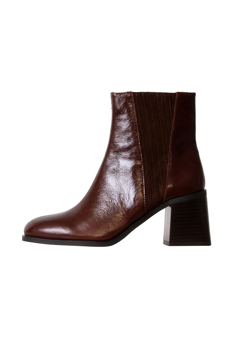 Bottines en cuir marron à bout pointu, avec des panneaux latéraux texturés et un talon bloc empilé. Fini lisse avec une apparence brillante.