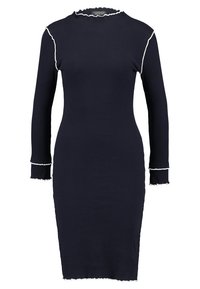 Granatowa, prążkowana sukienka z długim rękawem o dopasowanym kroju, z białymi falbankami wzdłuż dekoltu i mankietów.
