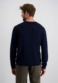Marineblauwe lange mouwen trui gemaakt van een zachte, gladde stof met een ronde halslijn en geribde manchetten, gecombineerd met bruine gestructureerde broeken.